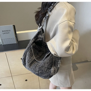 Détail du sac à bandoulière en denim gris montrant la texture délavée et les bords effilés