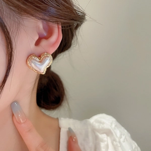 Detailed close-up of a heart-shaped pearl earring with a textured gold metallic border