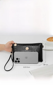 Close-up of elegant black crocodile pattern PU leather clutch with wristlet strap.
