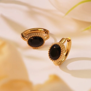 Détail de créoles dorées vintage avec zircon noir ovale et bordure perlée élégante