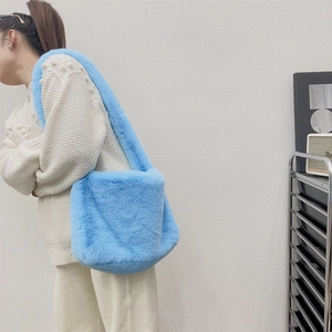 Close-up of fluffy light blue faux fur shoulder bag showing soft plush texture and wide strap