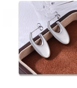 Close-up of minimalist U-shaped silver metal earrings with a polished mirror finish