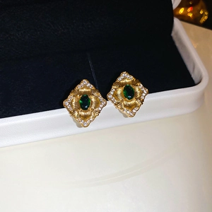 Détail de boucles d'oreilles vintage en or avec pierre verte et strass blancs