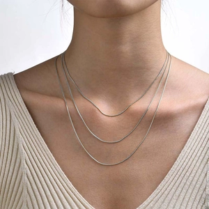 Close-up of triple layered silver snake chain necklace worn on neck to show fit