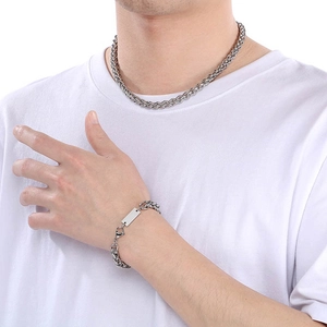Nahaufnahme der silbernen Edelstahl-Kordelkette und des Armbands mit quadratischem Anhänger