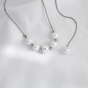 Detail view of multi-layered pearl and snake chain necklace on white satin silk