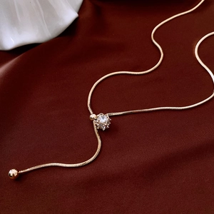Macro detail of gold-plated snake chain necklace with sparkling zircon cube pendant