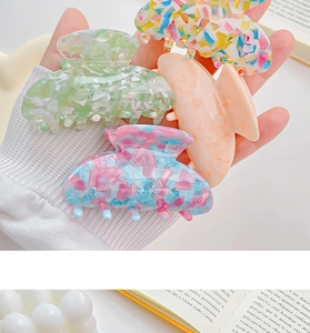 Detail of four acetate claw clips featuring floral and marble patterns for thick hair