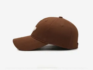 Side view of dark brown cotton baseball cap showing detailed white embroidery and stitching
