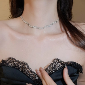 Close-up of silver-toned twisted wave necklace with rhinestones on model neck