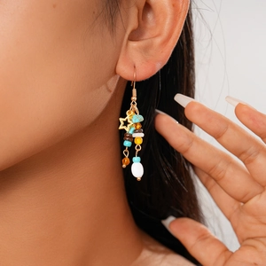 Detail of star charm earrings with colorful glass beads worn on model's ear
