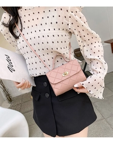 Pink quilted mini handbag with gold hardware held by a model in a modern interior setting