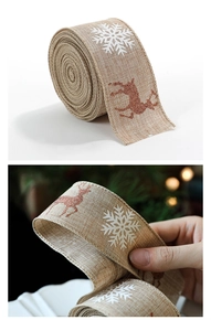Detail of burlap Christmas ribbon with white snowflakes and red glitter reindeer patterns