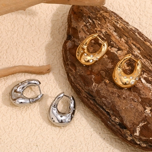 Macro shot of 18K gold and silver U-shaped twisted earrings with sparkling crystals