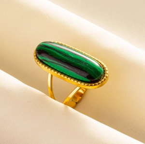 Makroansicht von Vintage-Goldring mit grünem Malachitstein auf Seidenstoff