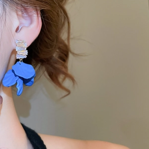 Detail shot of model wearing blue frosted petal earrings with sparkling cubic zirconia