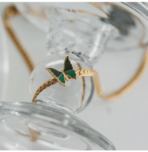 Close-up of a 18K gold plated chain anklet with a green enamel butterfly pendant