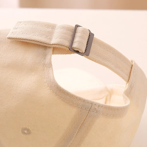 Detailed macro view of the adjustable metal buckle and cotton strap on the beige baseball cap