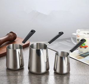Three sizes of stainless steel saucepans with black handles in a modern kitchen setting