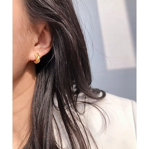 Detailed close-up of vintage matte gold twisted hoop earring worn by a model