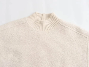 Close-up of the textured beige knit fabric and stand collar detail on this casual sweater