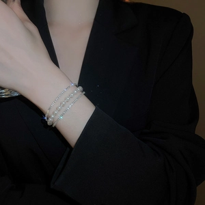Macro shot of layered silver bracelet featuring white pearls and sparkling rhinestones