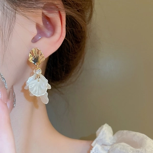 Close-up of elegant acrylic flower petal earrings with gold fan top on female model