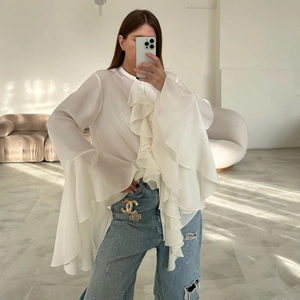 Elegant white chiffon blouse with ruffled layers and flared sleeves on casual denim