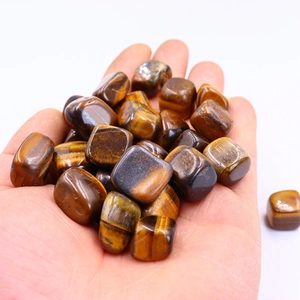 Polished natural Tiger Eye stones held in hand showing golden brown chatoyant texture