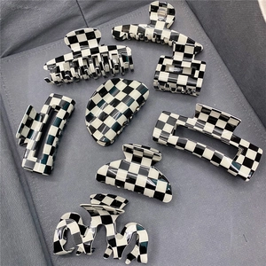 Collection of black and white checkered hair claws in various geometric shapes on grey fabric