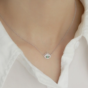 Detail of 925 silver evil eye pendant with green stone and sparkling zircon on a model