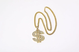 Detail of hip-hop gold dollar sign pendant necklace with iced-out crystals and curb chain