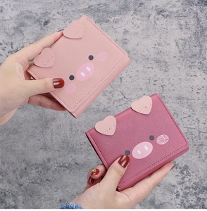 Detail of pink and red pig cartoon wallets with lychee texture and trifold design