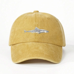 Close-up of ginger yellow washed cotton baseball cap featuring embroidered shark on front