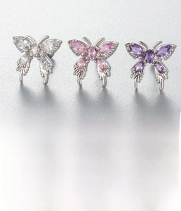 Détail macro du piercing papillon argenté orné de zircons blancs roses et violets