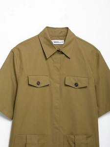Detail view of khaki utility shirt featuring buttoned chest pockets and durable twill fabric