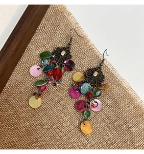 Detail of bohemian long drop earrings with colorful shell disks and bronze flower charms