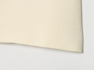 Close-up of premium cream knitted fabric texture with detailed ribbed stitching on the edge