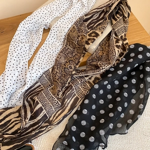 Flat lay detail of polka dot and animal print scarves on a natural wooden background