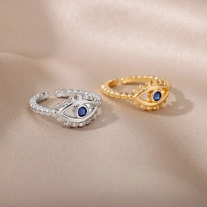 Macro shot of gold and silver open eye rings with blue stones on satin fabric
