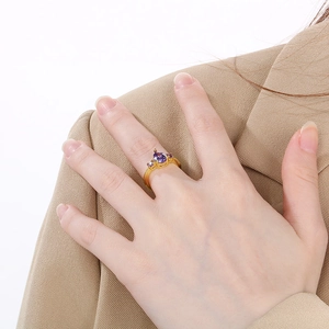 Detail of a gold stainless steel ring featuring a purple pear-cut zircon on model's hand