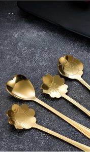 Makro-Detail von goldenen Edelstahllöffeln mit blüten- und herzförmigen Köpfen