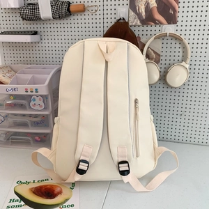 Minimalist beige backpack for students with adjustable straps on a stylish pegboard background