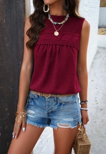 Detail of burgundy sleeveless blouse with lace trim and polka dot texture on high neck