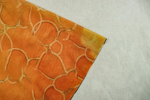 Close-up of orange and yellow marble pattern fabric on an A-line long-sleeve dress