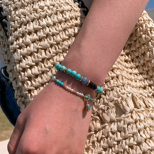 Bohemian beaded bracelet set with turquoise stones, white pearls and gold charms on wrist