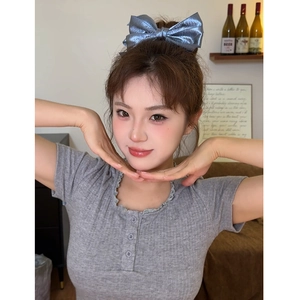 Detail of blue metallic triple bow hair claw clip worn by a model in a cozy indoor setting