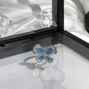 Detailed shot of a silver butterfly ring with blue enamel and pavé crystals on silk