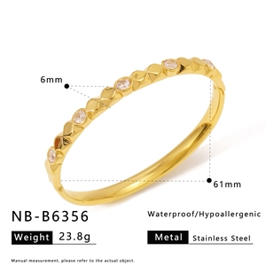 Detail view of gold-plated stainless steel bangle with inlaid stones and polished finish