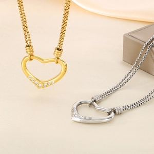 Detail of gold and silver hollow heart necklaces with zircons on a thick wheat chain